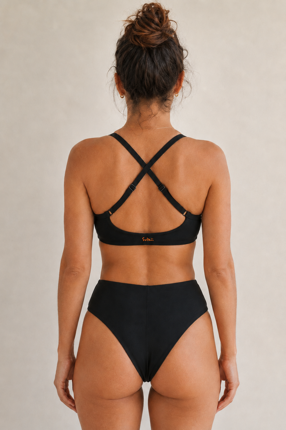 A model wearing Sulkii Drew High Waist Brief shown from the back with the Drew Cross Back Bra.